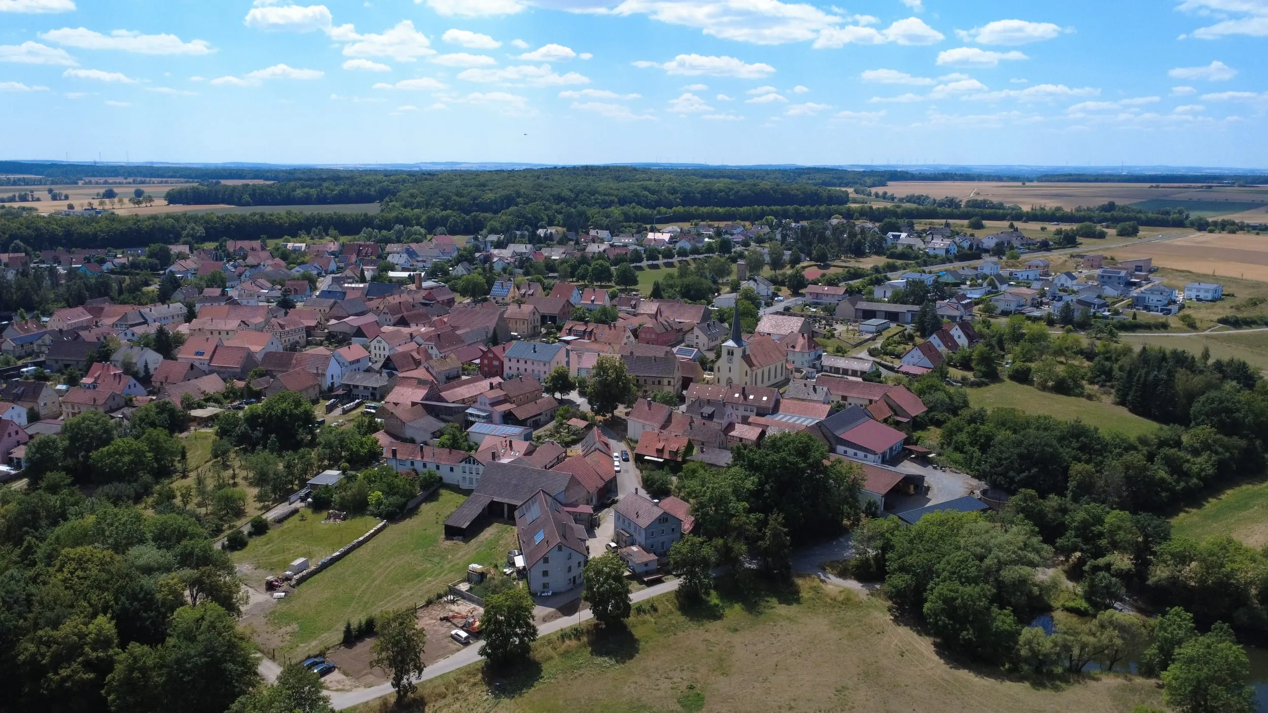 Luftbild von Untereuerheim aus größerer Höhe, weiter blauer Sommerhimmel über dem Ort mit der Pfarrkirche St. Gallus.