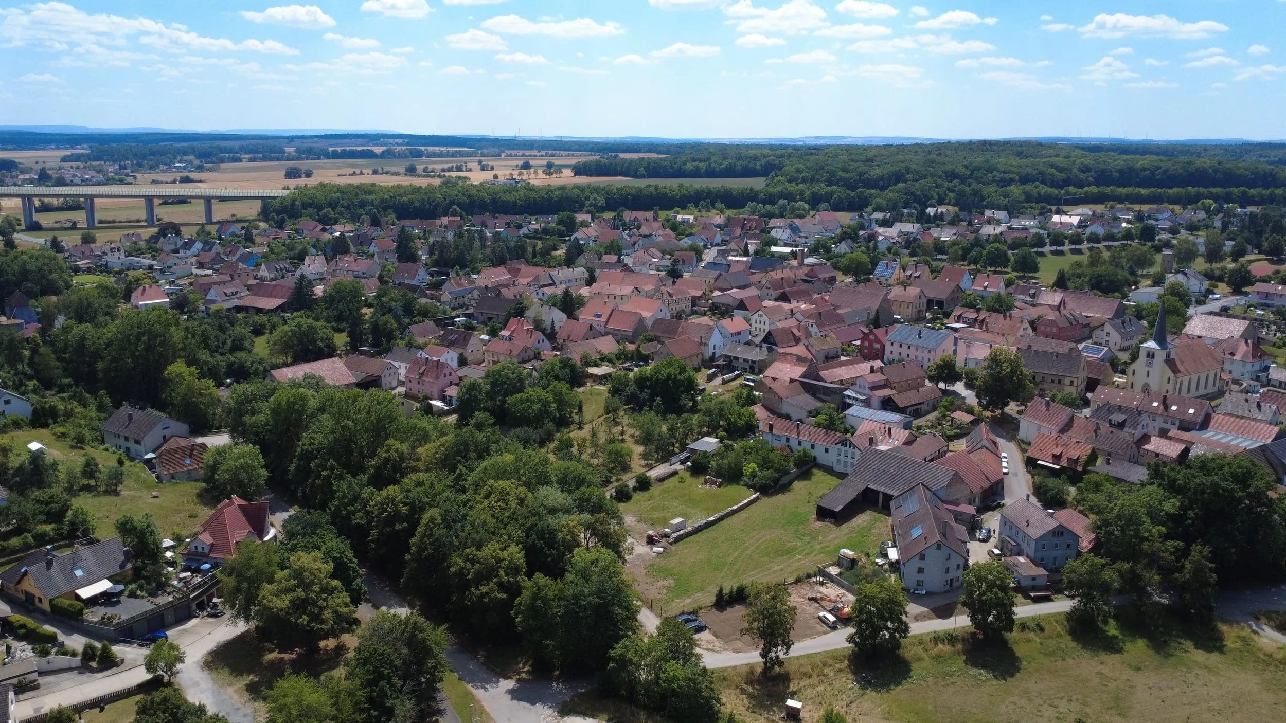 Luftbild von Untereuerheim mit Blick über die Dächer bis zu einer Talbrücke im Hintergrund.